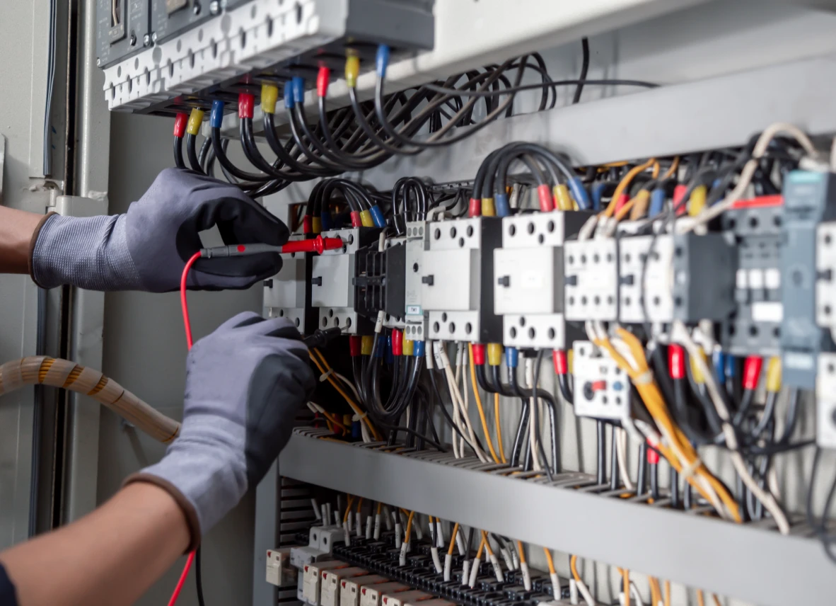 Electrician testing wires in control panel