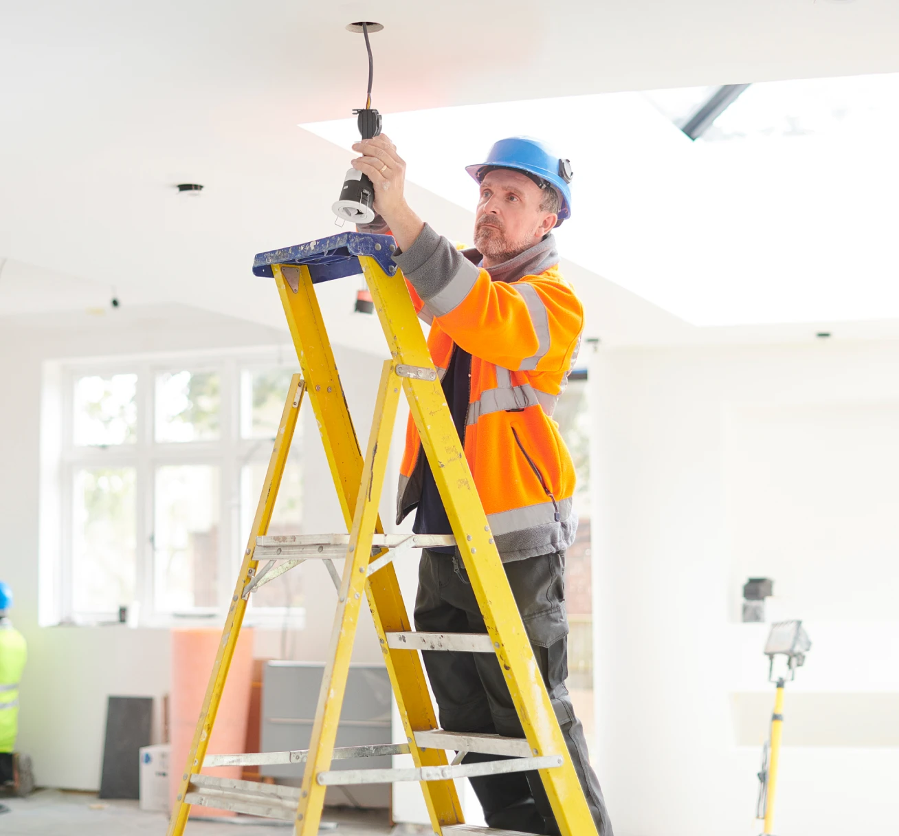 Electrician repairing ceiling light fixture